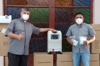 Two men wearing masks and standing next to boxes.