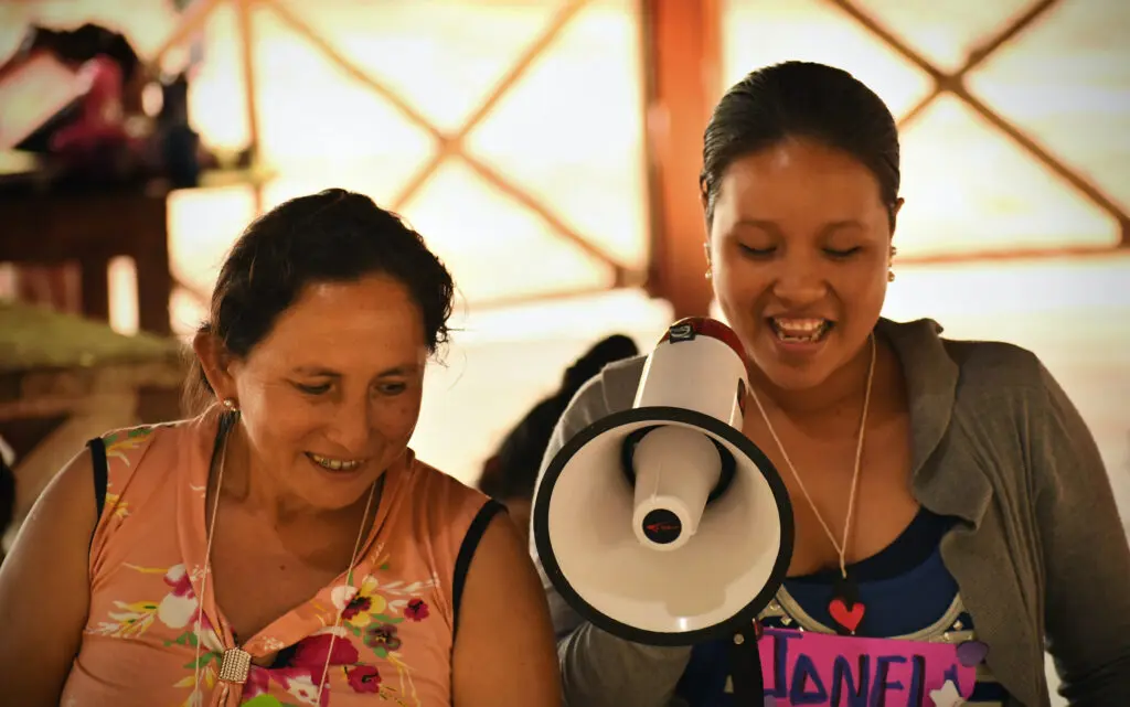 Two women are smiling while one of them is holding a megaphone.