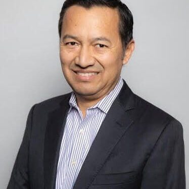 A man in a suit and tie smiling for the camera.