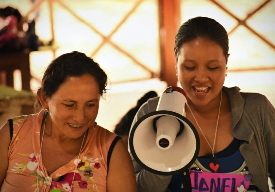 Two women are smiling while one of them is holding a megaphone.