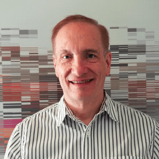 A man with red hair and striped shirt smiling.