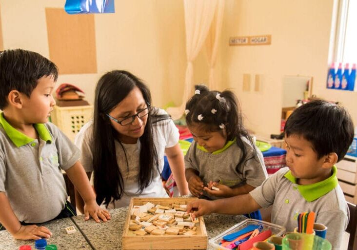 A woman and two children playing with a wooden toy.